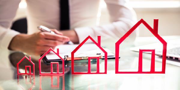Generic red house outlines overlaying a desk with a person over a clipboard