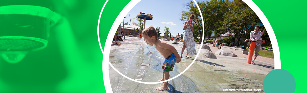 This is a picture of a little boy playing in a water park on a sunny day.