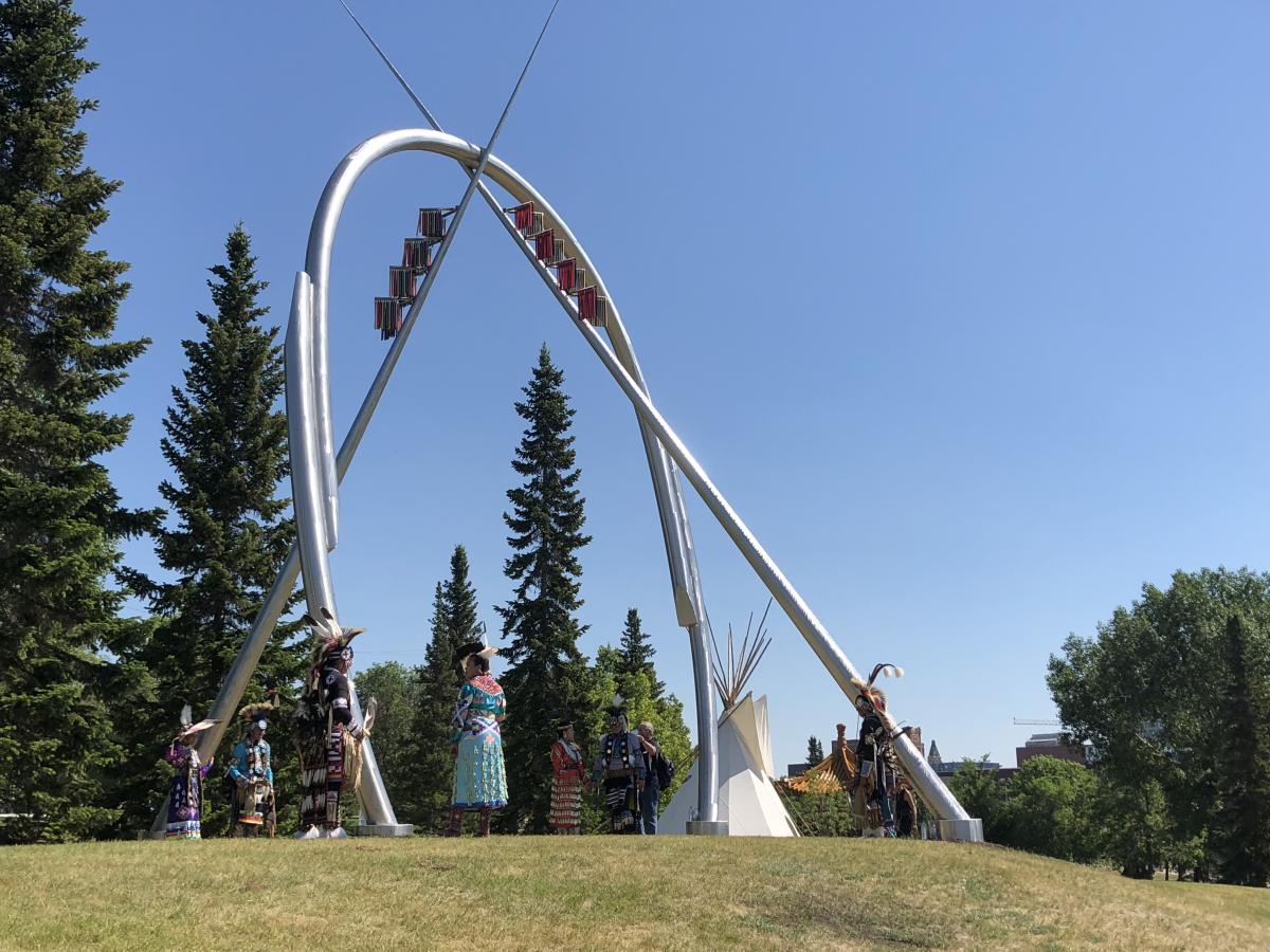 Silver sculpture with two poles crossing over an oval structure