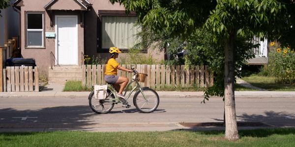 A lady riding a bicycle in front of a house 